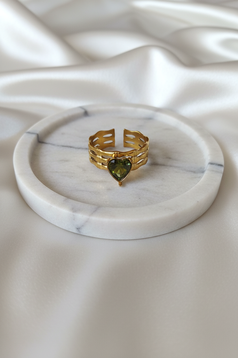 Bague ajourée dorée cœur vert sur plateau marbré