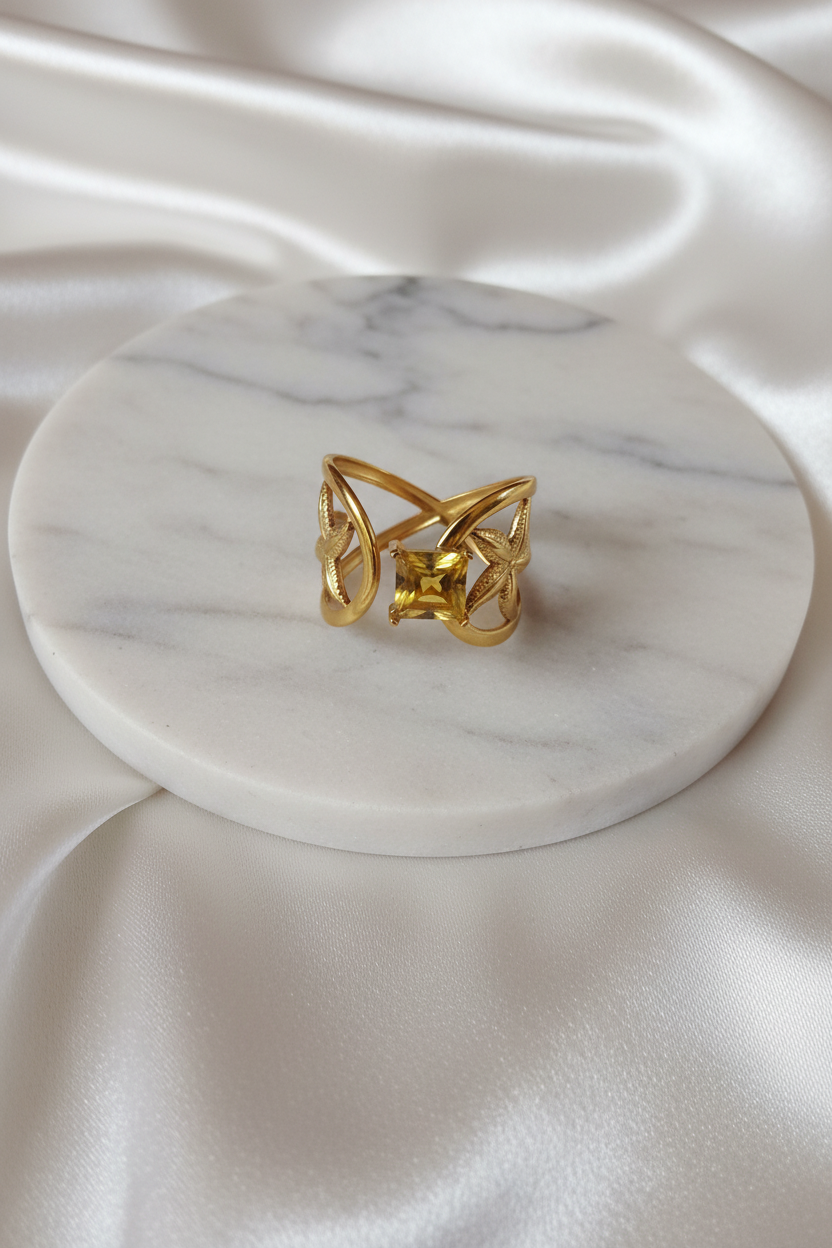 Bague feuilles dorée pierre jaune sur plateau marbré