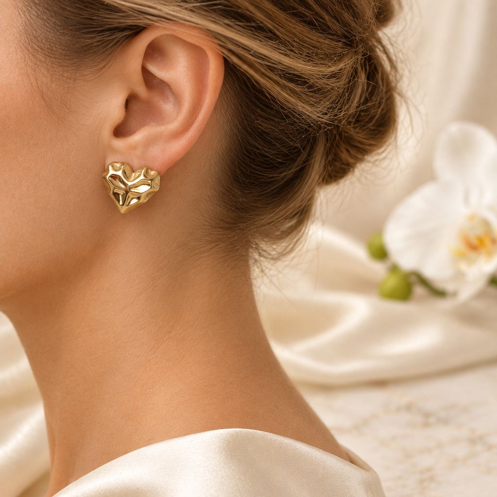Boucle cœur dorée portée à l’oreille gauche dans le même décor élégant