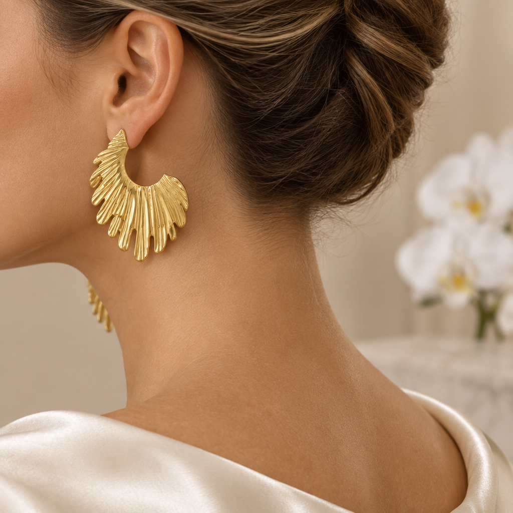 Boucle dorée ajourée portée à l’oreille gauche dans le même décor élégant