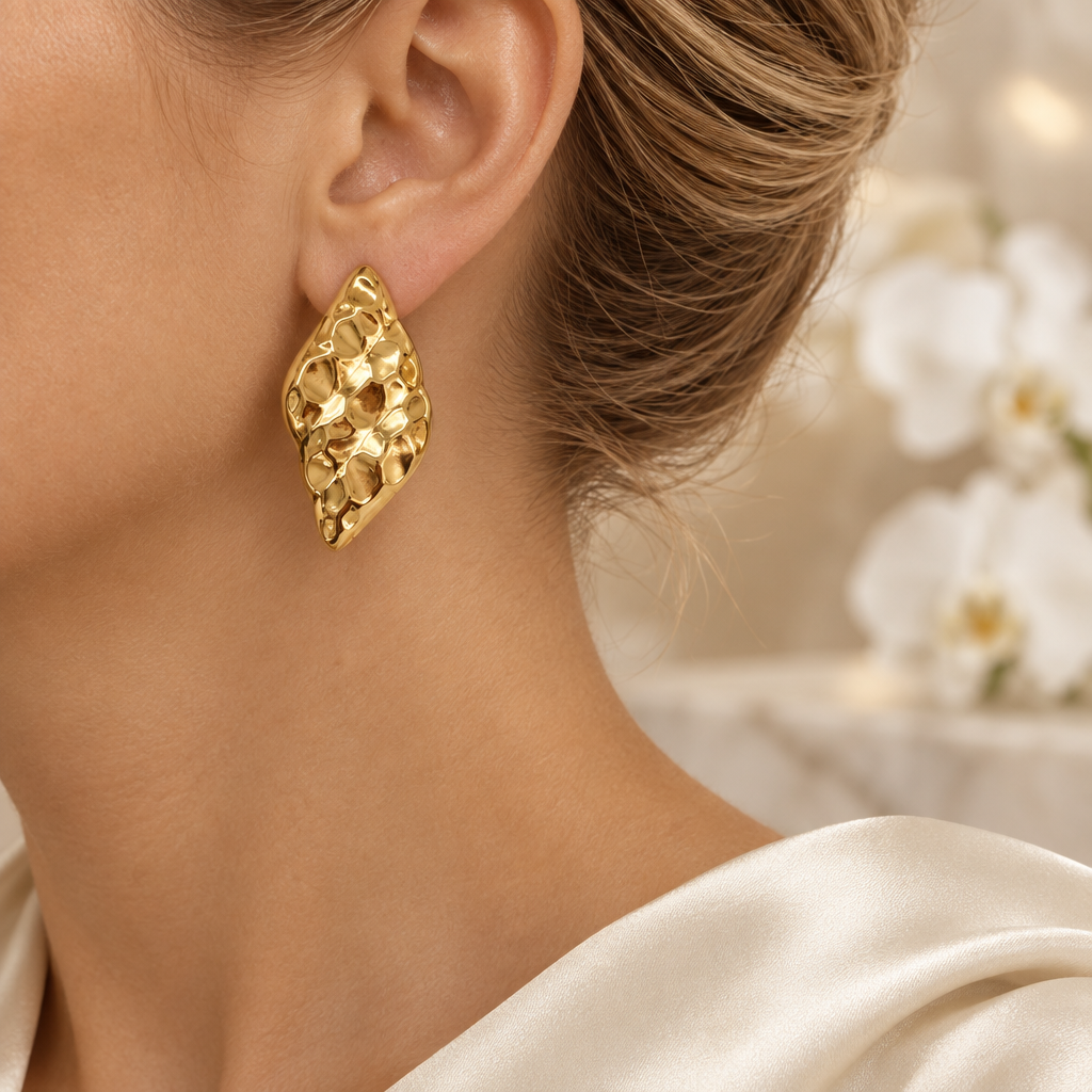Boucle dorée martelée portée à l’oreille gauche dans le même décor élégant