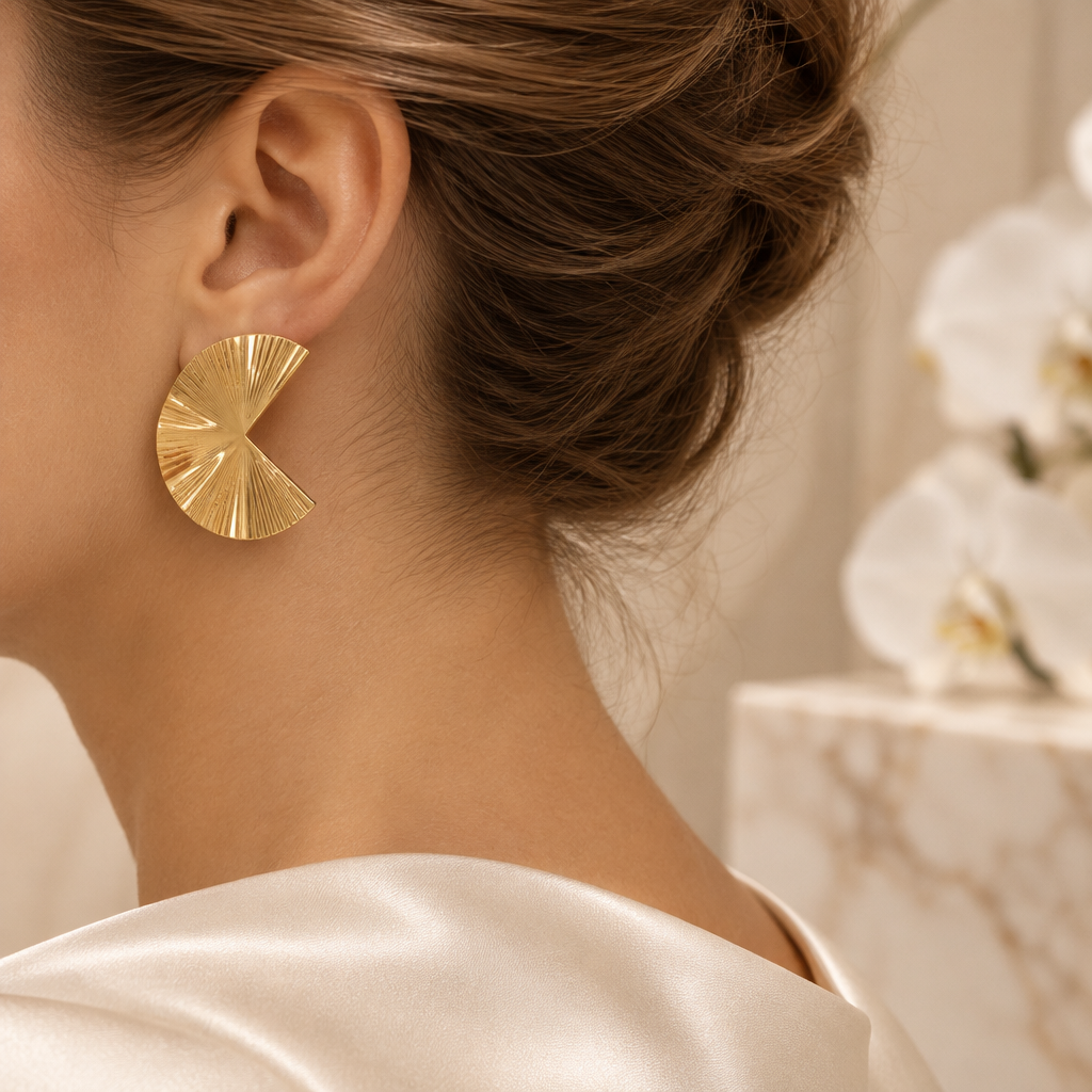 Boucle dorée striée portée à l’oreille gauche dans le même décor élégant