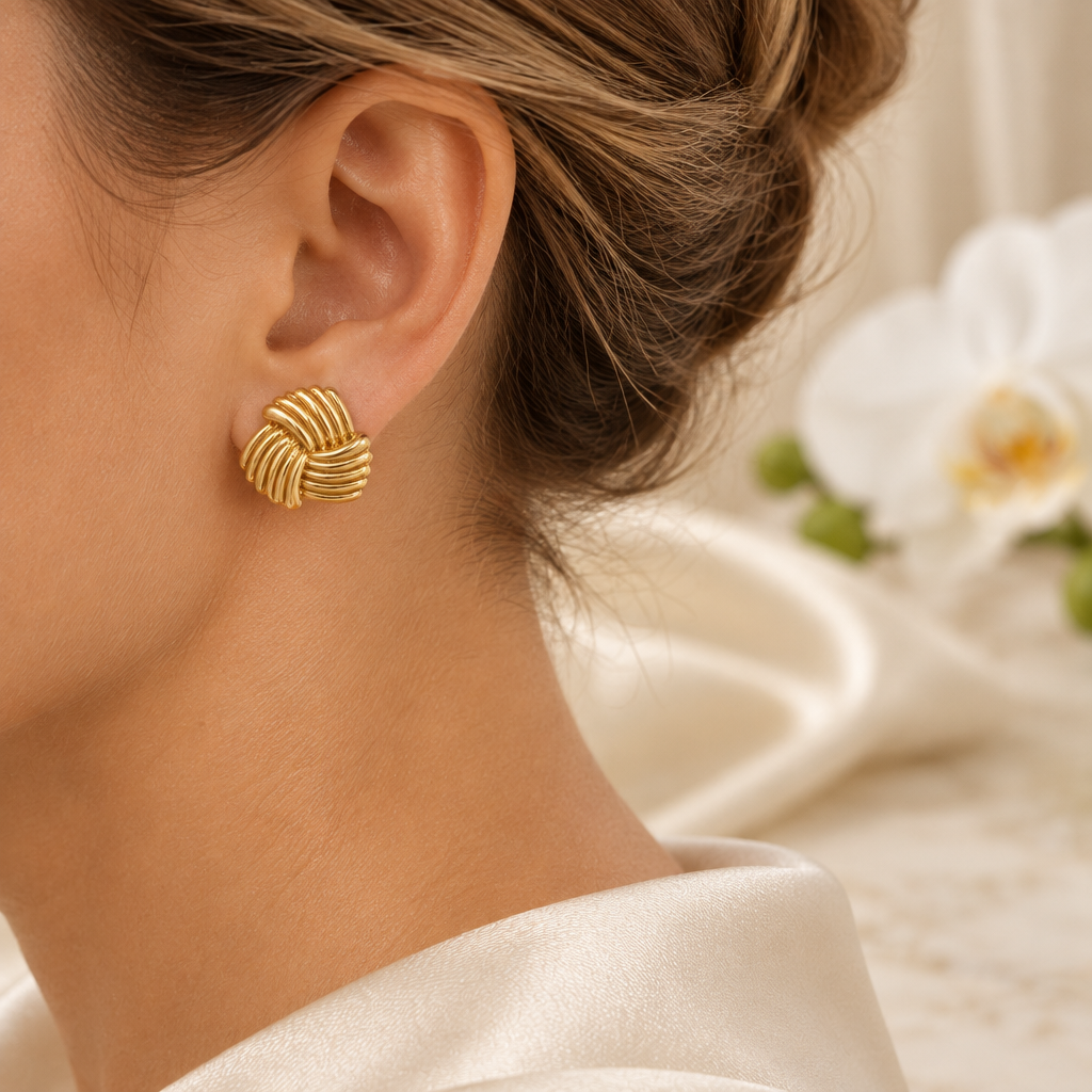 Boucle dorée striée portée à l’oreille gauche, même décor élégant