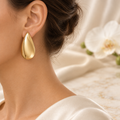 Boucle goutte dorée portée à l’oreille gauche dans le même décor chic