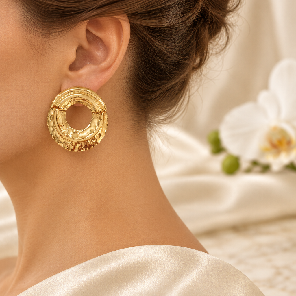 Boucle ovale dorée portée à l’oreille gauche dans le même décor élégant