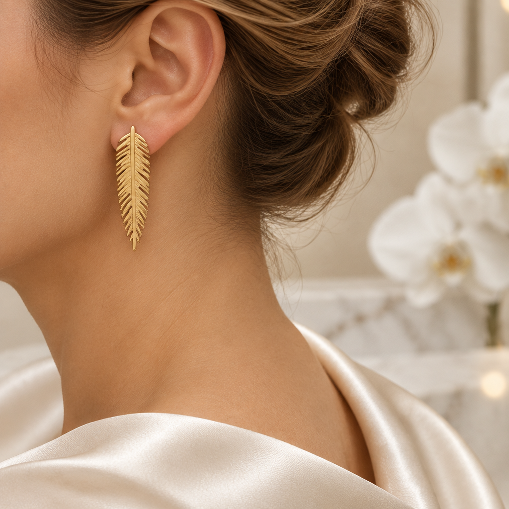 Boucle plume dorée portée à l’oreille gauche dans le même décor élégant