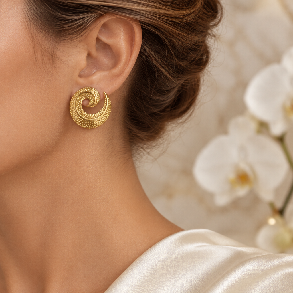 Boucle spirale dorée portée à l’oreille gauche dans le même décor élégant