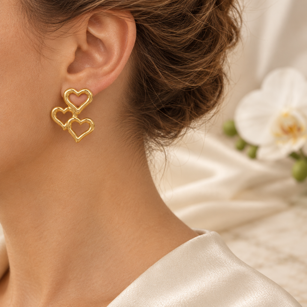 Boucle à trois cœurs dorés portée à l’oreille gauche dans le même décor élégant