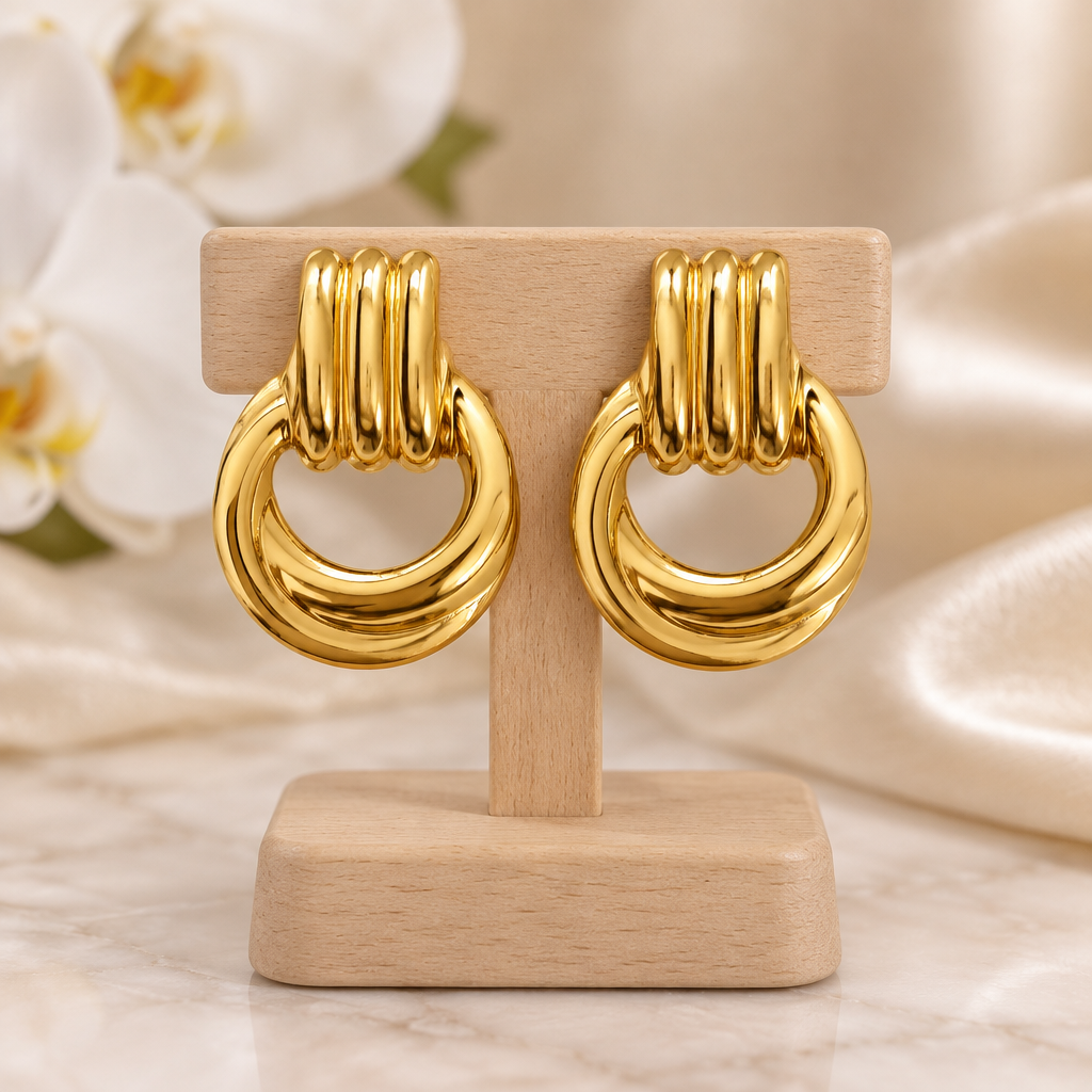 Boucles anneaux dorés sur un présentoir en bois dans un décor chic