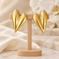Boucles cœurs allongés dorés sur un présentoir en bois dans un décor chic