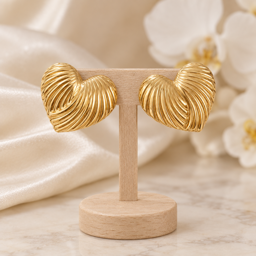 Boucles cœurs dorés striés sur un présentoir en bois dans un décor chic