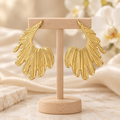 Boucles dorées ajourées sur un présentoir en bois dans un décor chic