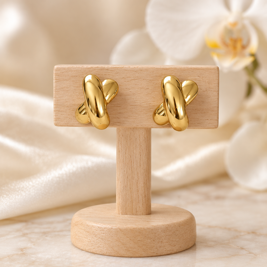 Boucles dorées croisées sur un présentoir en bois dans un décor chic