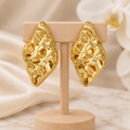 Boucles dorées martelées sur un présentoir en bois dans un décor chic