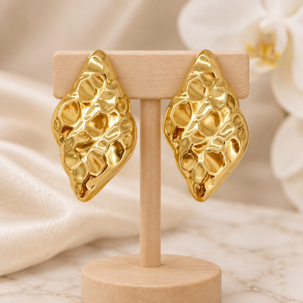 Boucles dorées martelées sur un présentoir en bois dans un décor chic