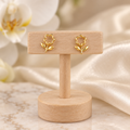 Boucles fleurs ajourées dorées sur un présentoir en bois dans un décor chic