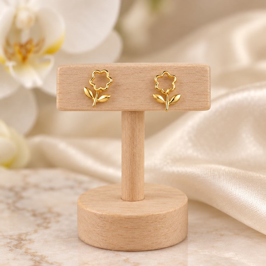 Boucles fleurs ajourées dorées sur un présentoir en bois dans un décor chic