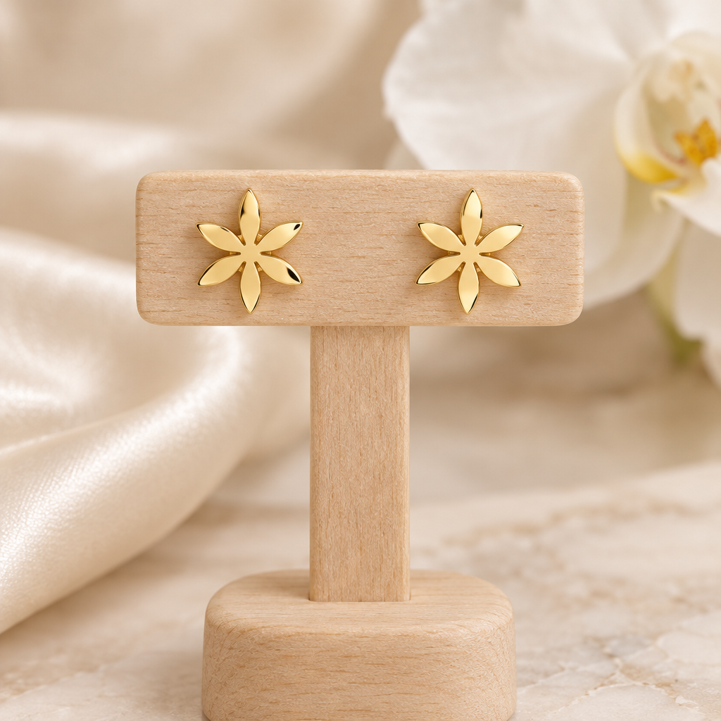 Boucles fleurs dorées à six pétales sur un présentoir en bois dans un décor chic