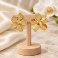 Boucles fleurs dorées sur un présentoir en bois dans un décor chic