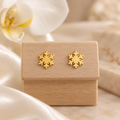Boucles flocons dorés sur un présentoir en bois dans un décor chic