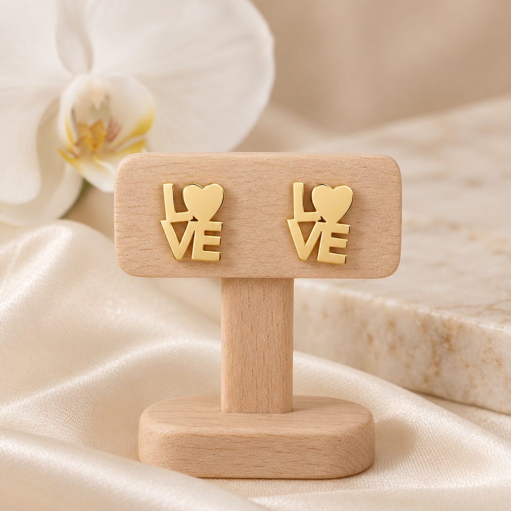 Boucles LOVE dorées sur un présentoir en bois dans un décor chic