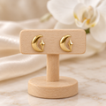 Boucles lune et étoile dorées sur un présentoir en bois dans un décor chic