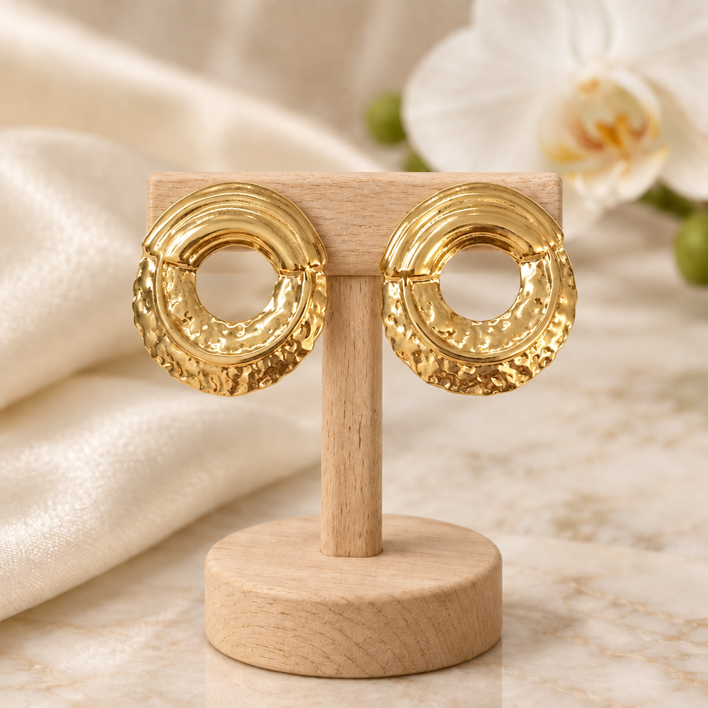 Boucles ovales dorées sur un présentoir en bois dans un décor chic