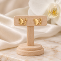 Boucles papillons dorés sur un présentoir en bois dans un décor chic