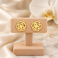 Boucles roses ajourées dorées sur un présentoir en bois dans un décor chic