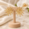Boucles soleil dorées sur un présentoir en bois dans un décor chic