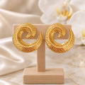 Boucles spirales dorées texturées sur un présentoir en bois dans un décor chic