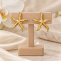 Boucles étoiles de mer dorées sur un présentoir en bois dans un décor chic