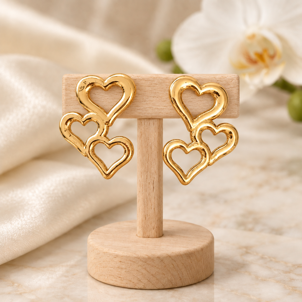 Boucles à trois cœurs dorés sur un présentoir en bois dans un décor chic