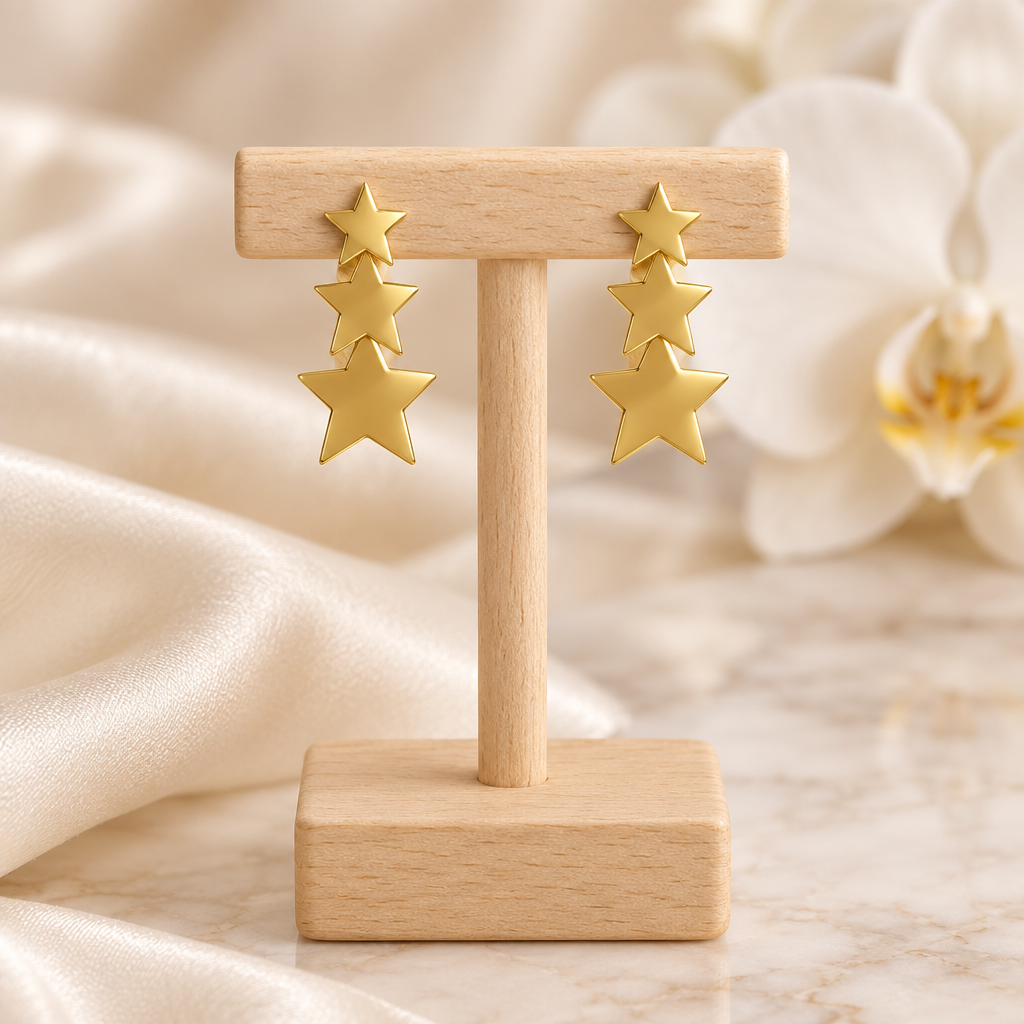 Boucles à trois étoiles dorées sur un présentoir en bois dans un décor chic